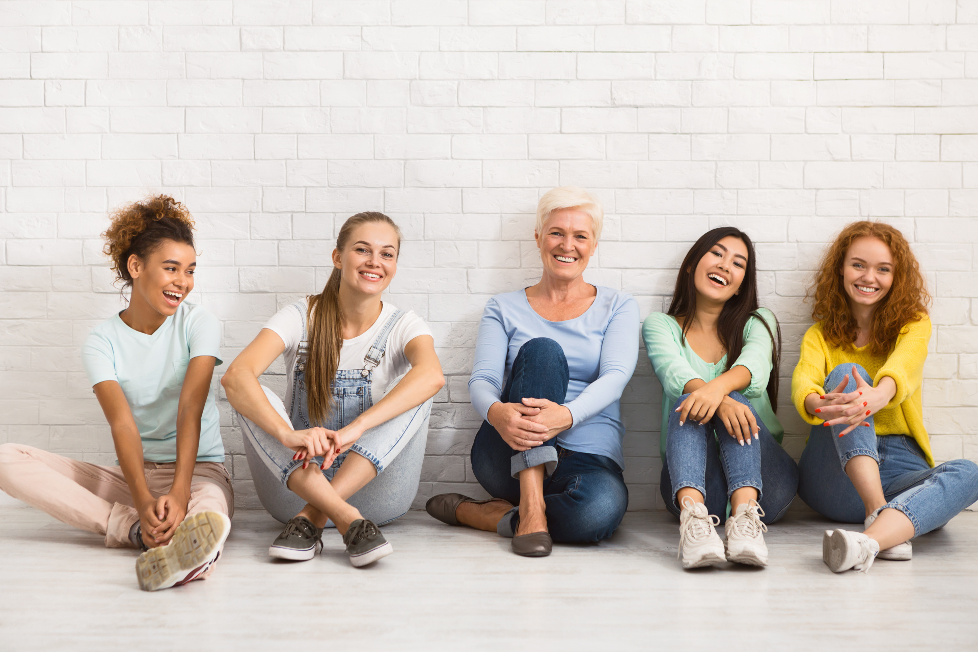 Ladies Of Different Age Smiling Sitting Together On Floor Indoor