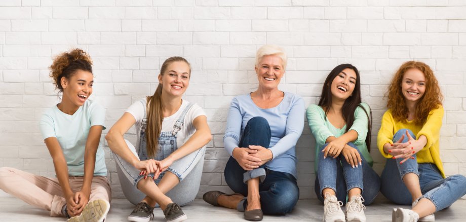 Ladies Of Different Age Smiling Sitting Together On Floor Indoor