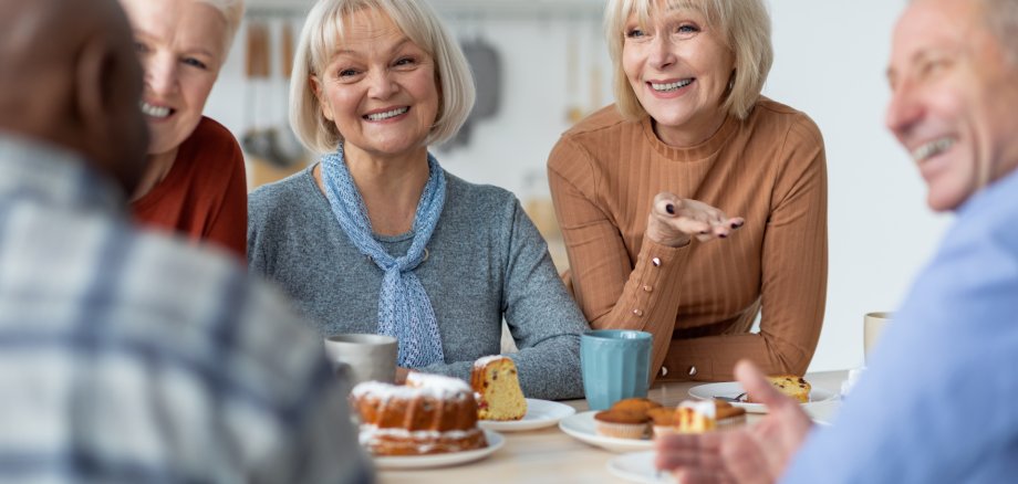 Eine gemischte Gruppe Menschen bei Kaffee und Kuchen.