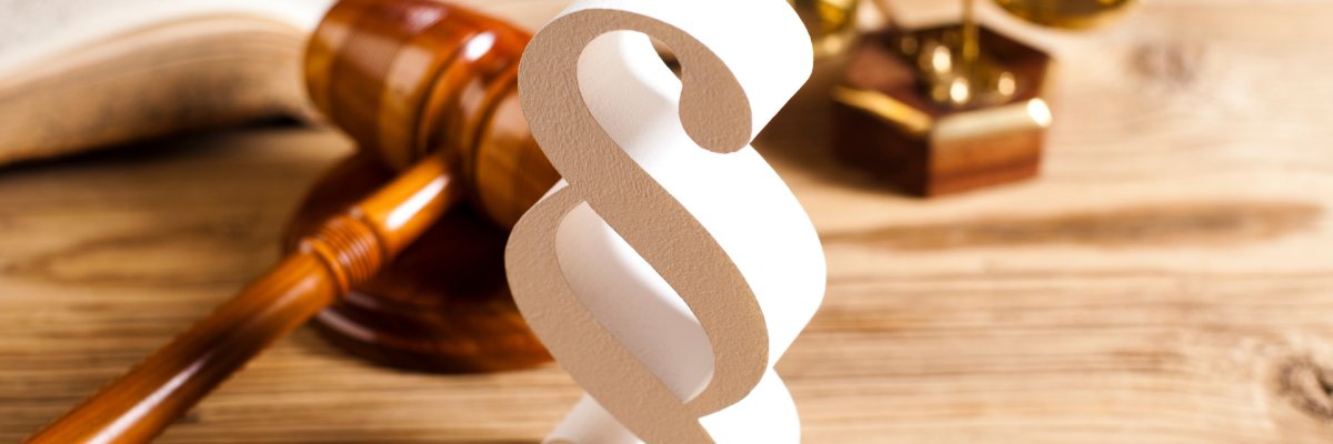Ein Holz-Paragraph, ein Richterhammer und die Waage des Gerichts.
