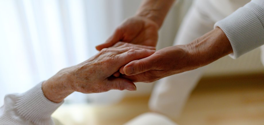 Rentnerin wird bei den Händen gehalten, Fürsorge im Alter Zwei Hände die eine ältere Hand umschließen