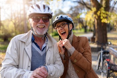 Lachendes älteres Ehepaar mit Fahrradhelmen auf dem Kopf