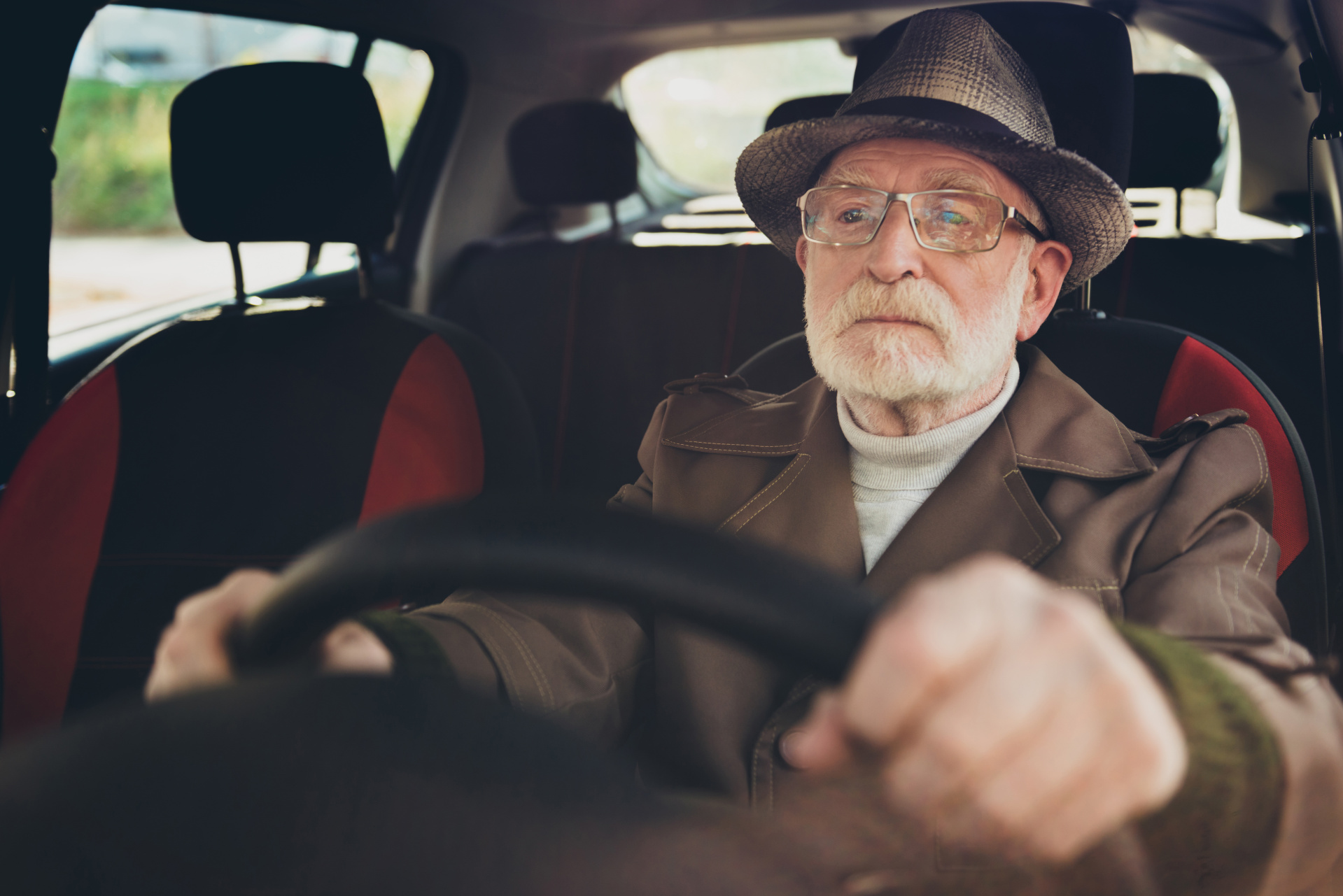 Close-up portrait of his he nice focused serious grey-haired man driving car in traffic jam studying learning rules holding steering wheel getting work