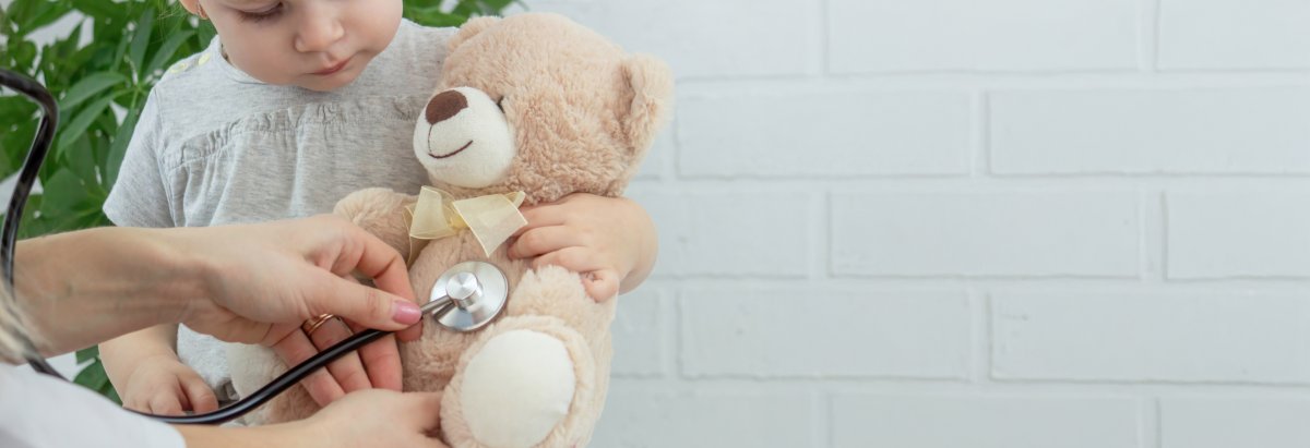 Kind mit einem kranken Teddybär der von einer Ärztin untersucht wird