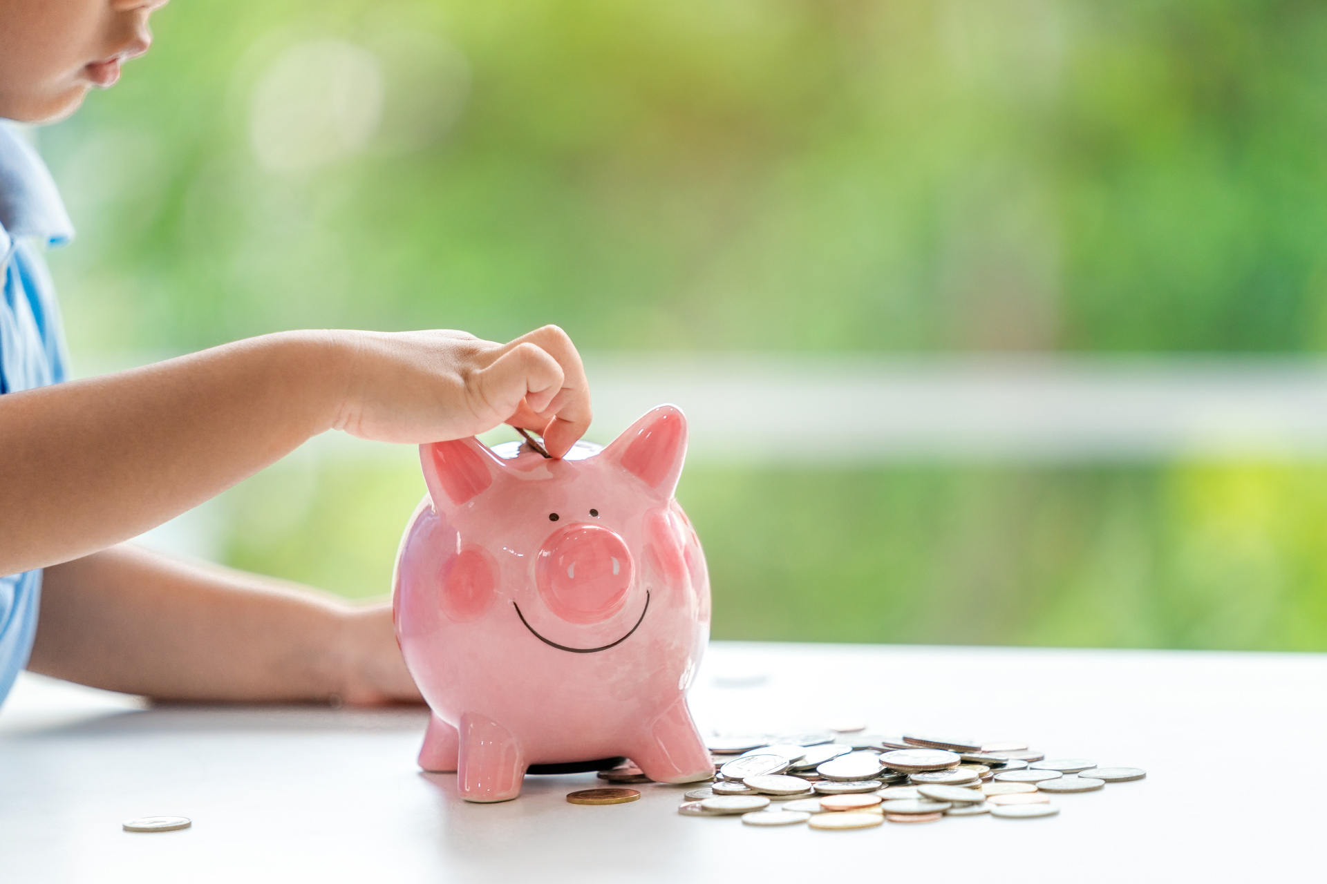 Kind mit Sparschwein Eine kleiner Junge steckt Geld in sein Sparschwein