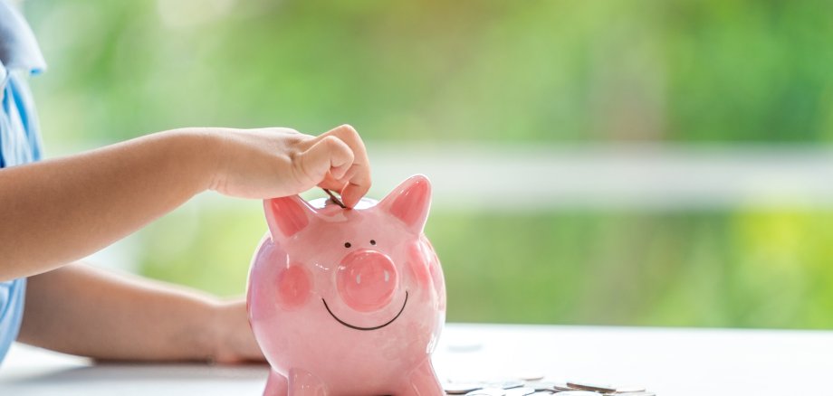 Kind mit Sparschwein Eine kleiner Junge steckt Geld in sein Sparschwein