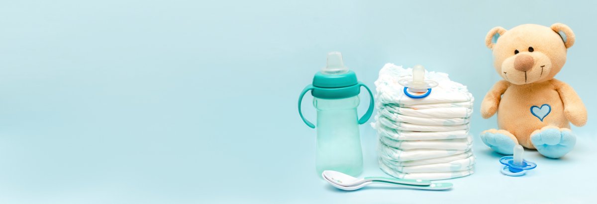 Ein Teddybär, Windeln und Babyflasche mit einem Löffel