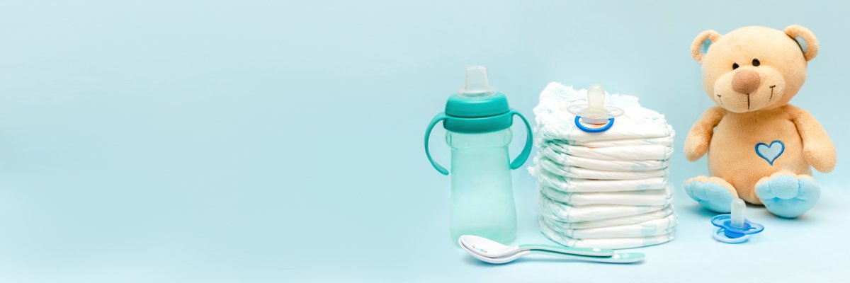 Baby-Erstausstattung Ein Teddybär, Windeln und Babyflasche mit einem Löffel
