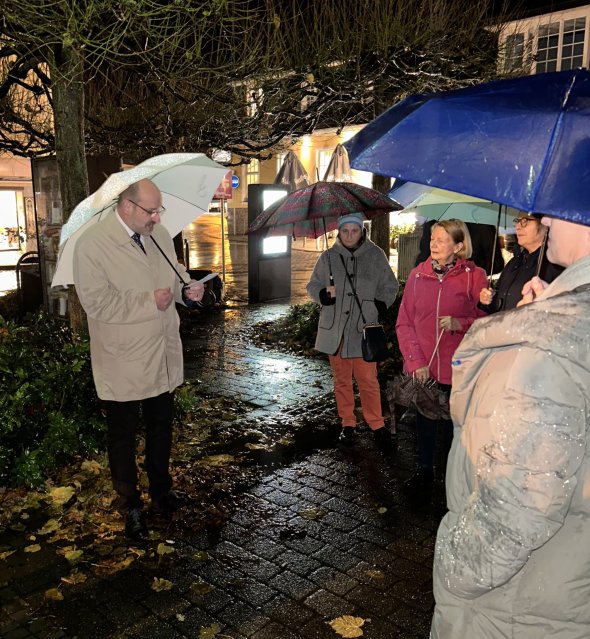 Menschen die mit Regenschirmen auf dem Bahnhofsvorplatz in Overath stehen