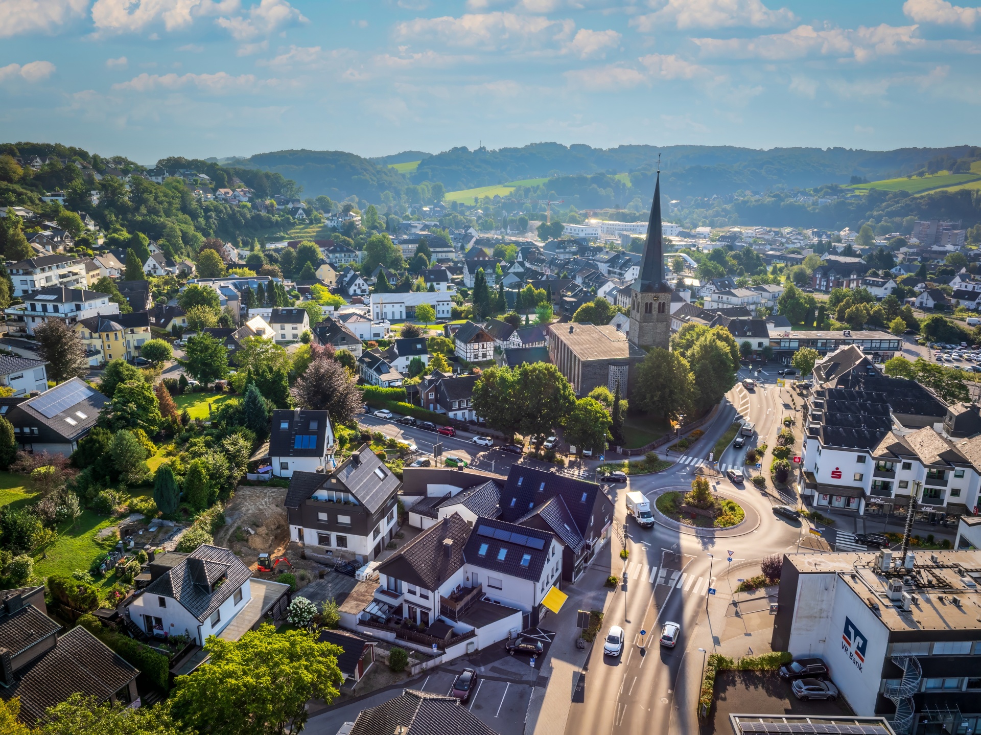 Luftbild von Overath Ein Blick aus der Luft auf das Zentrum von Overath mit der Kirche und den umliegenden Häusern vor einer grünen Hügellandschaft.