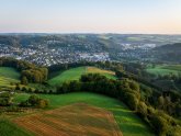 Stadt Overath Luftaufnahme von Overath mit Wohngebieten, grünen Wiesen, Wäldern und hügeliger Landschaft.