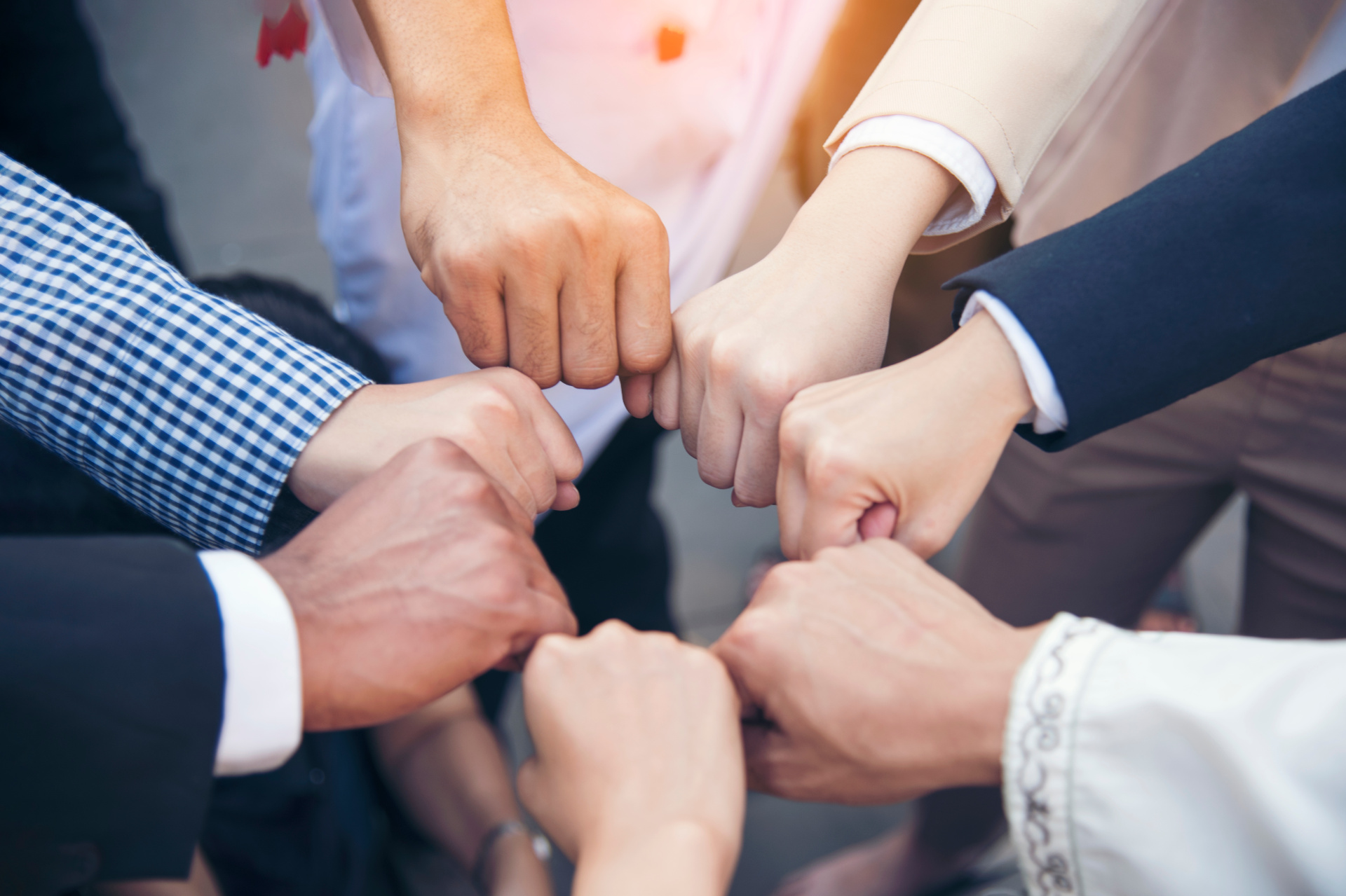 Verschiedene Menschen halten ihre Fäuste im Kreis zusammen.