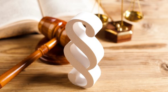 Ein Holz-Paragraph, ein Richterhammer und die Waage des Gerichts.