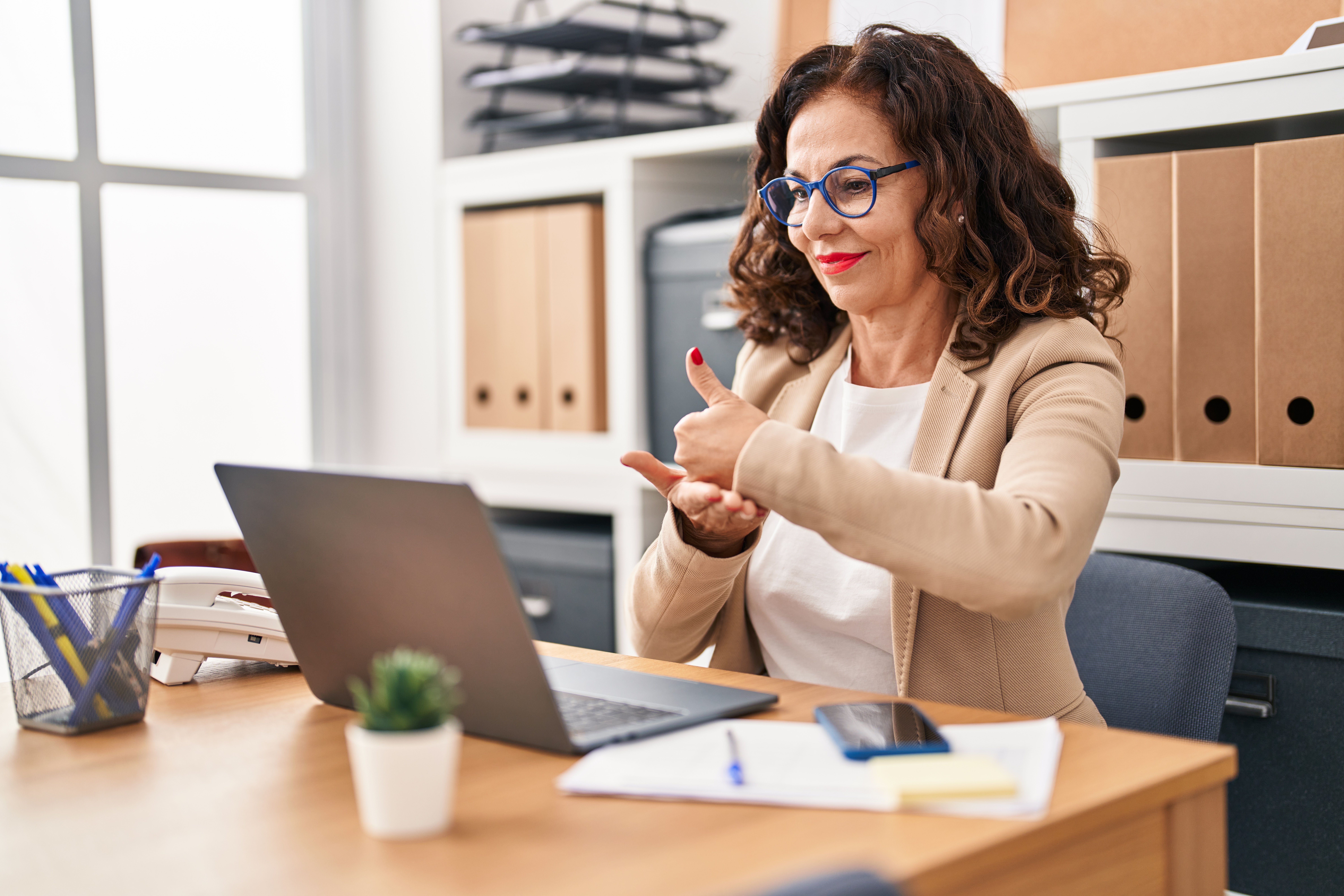 Eine Frau die vor einem Laptop sitzt und in Gebärdensprache etwas erklärt