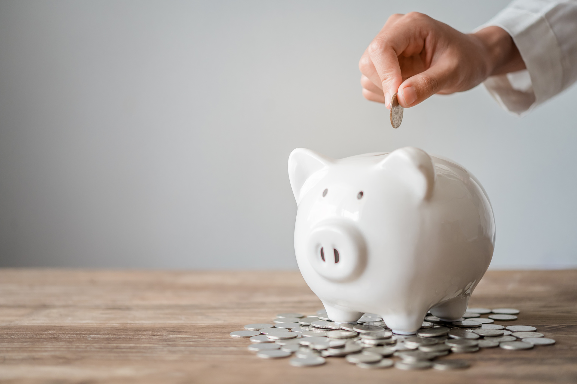 Eine weibliche Hand wirft Geld in ein Sparschwein