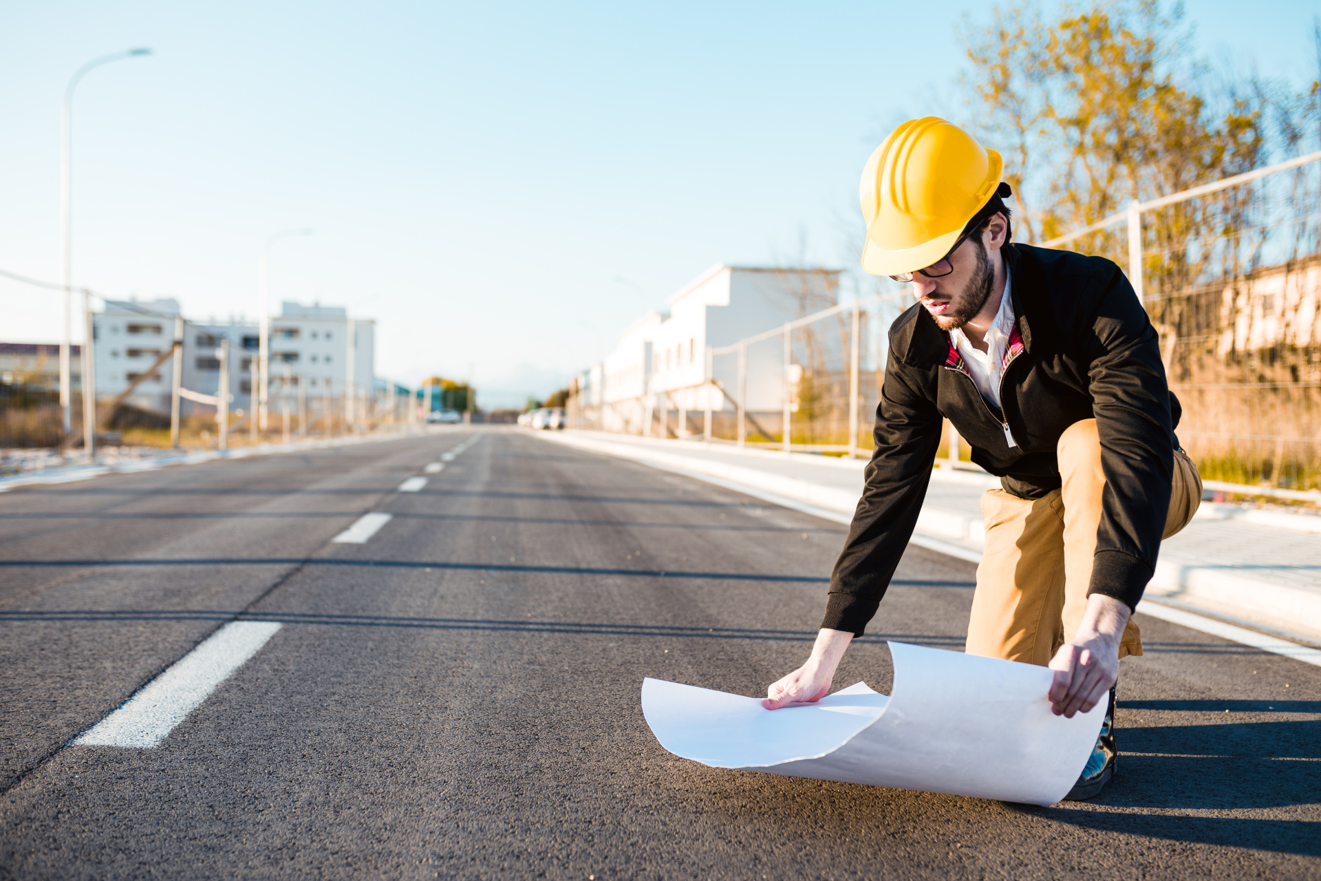 Ein Ingenieur der auf einer Straße sich einen Bauplan anschaut