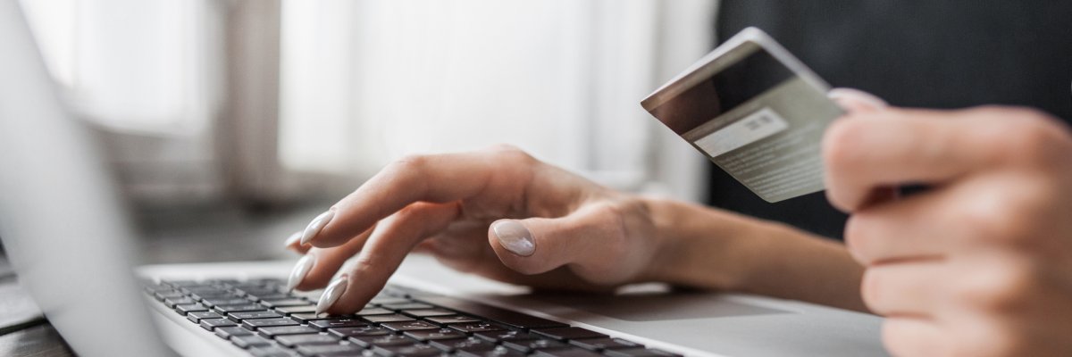 Eine Person die eine finanzielle Überweisung mit einer Kreditkarte in der Hand tätigt