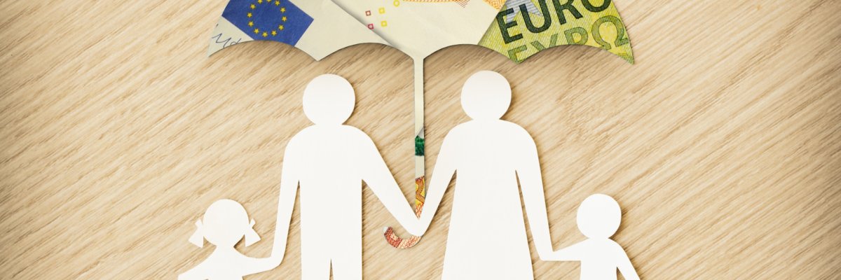 Eine Papierfamilie die unter einem Geldregenschirm steht