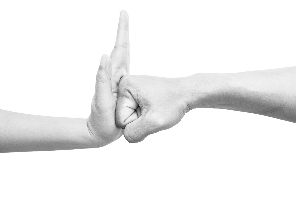Eine Hand zur Faust geballt die gegen die offene Hand drückt