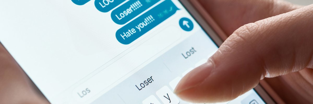 panoramic shot of abuser sending offensive messages while using smartphone, illustrative editorial