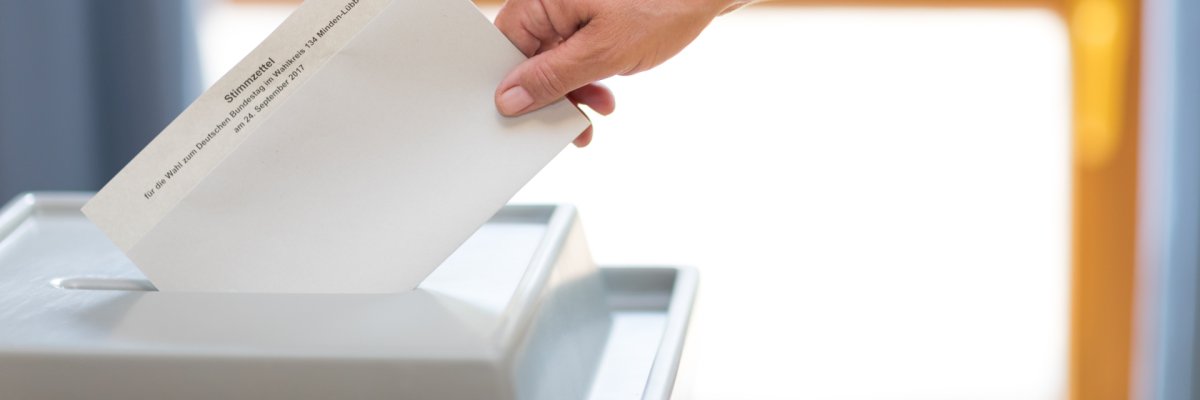 Stimmzettel wird in Wahlurne geworfen