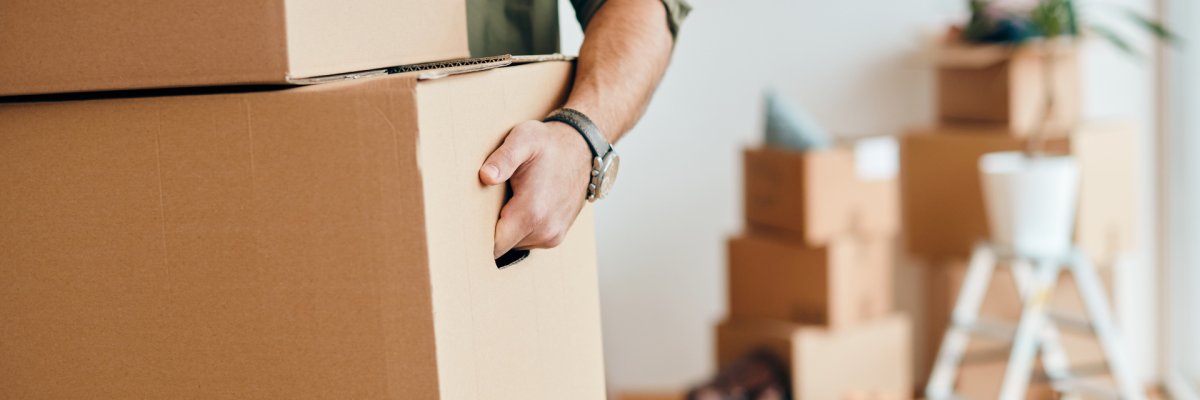 Close-up of man carrying cardboard boxes while relocating into new apartment.