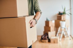 Close-up of man carrying cardboard boxes while relocating into new apartment.