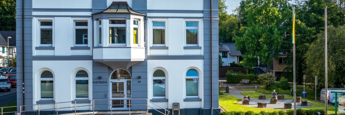Das weiße Gebäude des Rathauses mit grauen Akzenten und einem dunklen Ziegeldach.