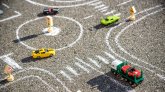 Toy cars red green blue color on the road chalked on black asphalt. Difficult traffic rules concept