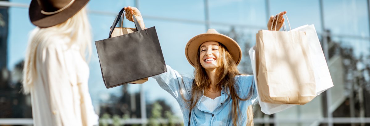 Two happy girlfriends walking with shopping bags in front of the shopping mall, feeling satisfied with new purchases Zwei glückliche Frauen mit Einkaufstüten