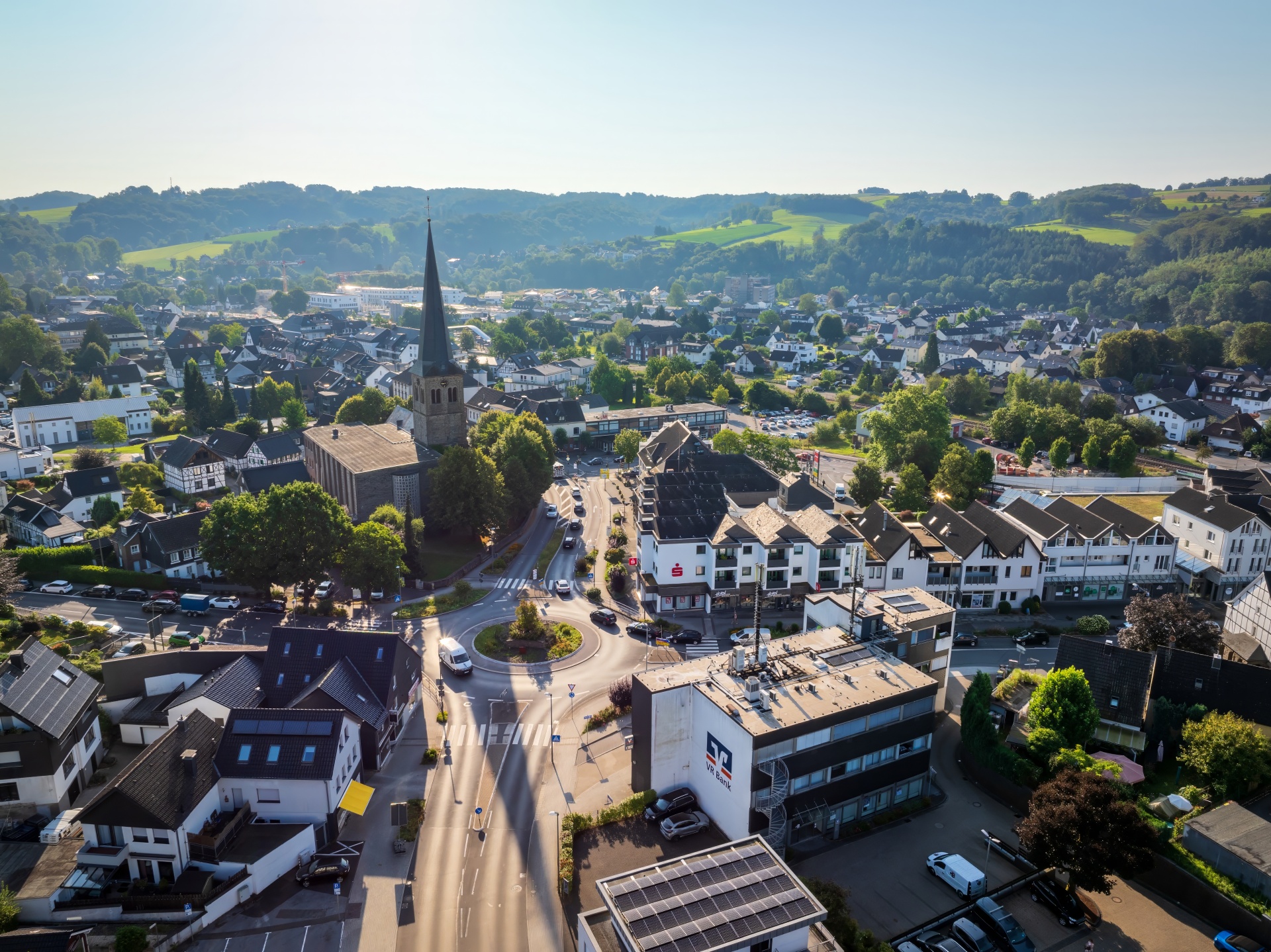 Luftbild Overath Zentrum Luftaufnahme des Ortskerns von Overath mit der markanten Kirche und dem zentralen Kreisverkehr vor einer grünen Hügellandschaft.