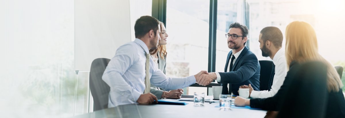 Zwei Männer die sich in einer Runde die Hand geben